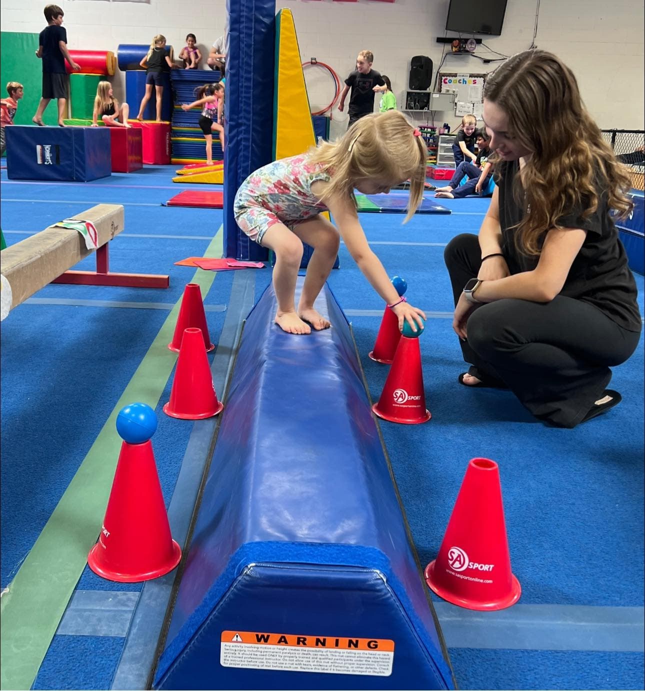 little girl touching cones on beam