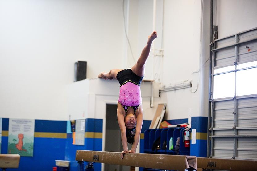 girl in upside down split handstand on beam